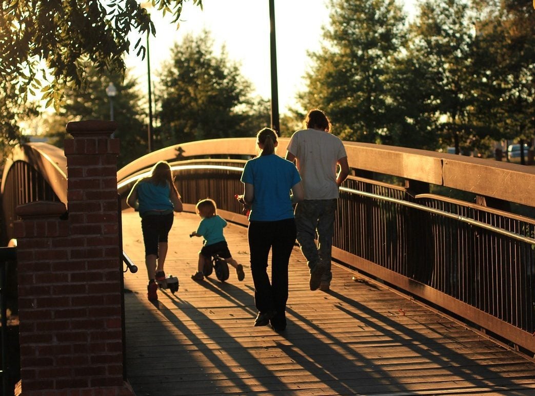 family walking over a bridge wth kids on a tricycle