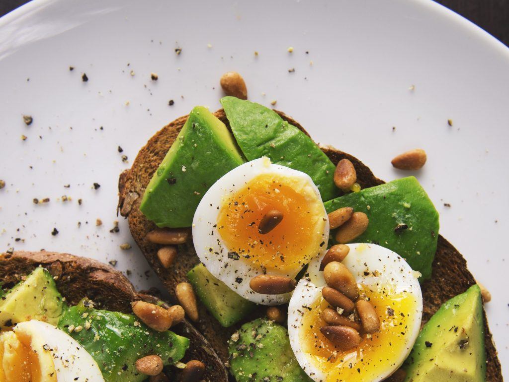avocado, soft boiled eggs with yolks, and pinenuts on toast