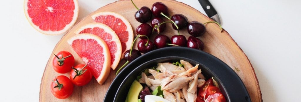 Preparing a dinner plate with tomatoes cherries grapefruit eggs avocado chicken apples and lettuce