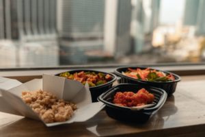 Delivered food in takeout containers, including rice, vegetables, and chicken