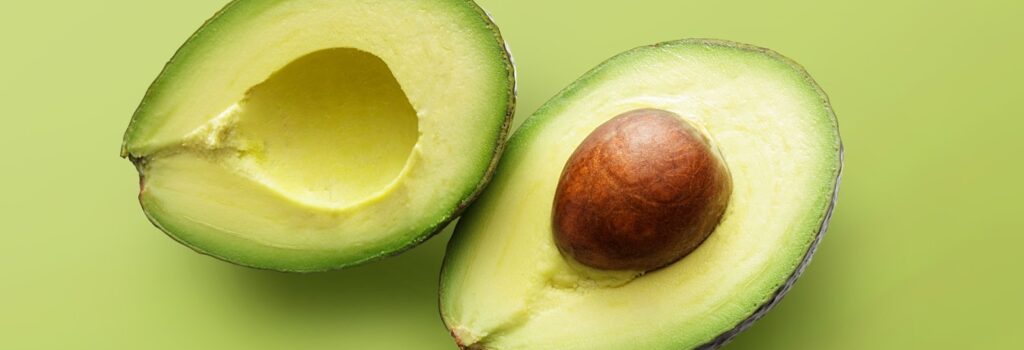 avocado cut in half on green background