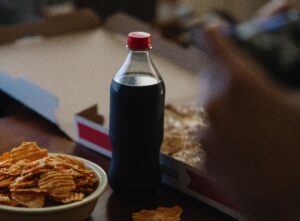 bottle of soda next to pizza and chips