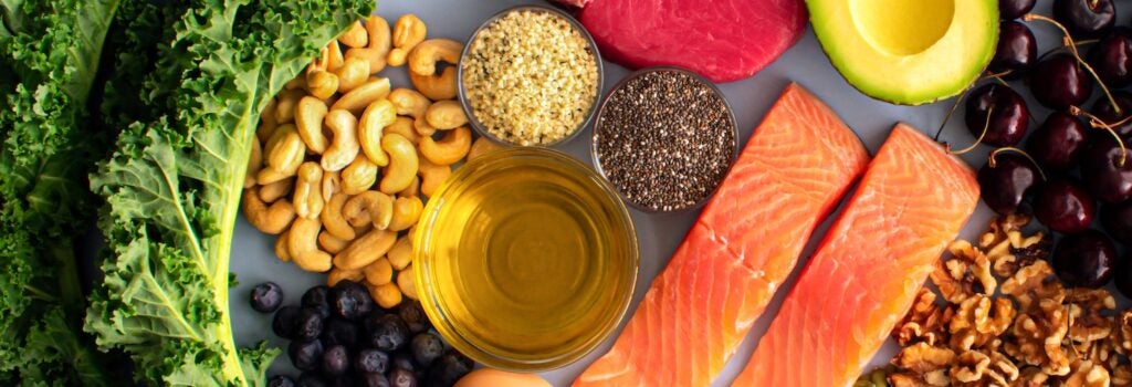 Overhead View of Fresh Omega-3 Rich Foods: A variety of healthy foods like fish, nuts, seeds, fruit, vegetables, and oil