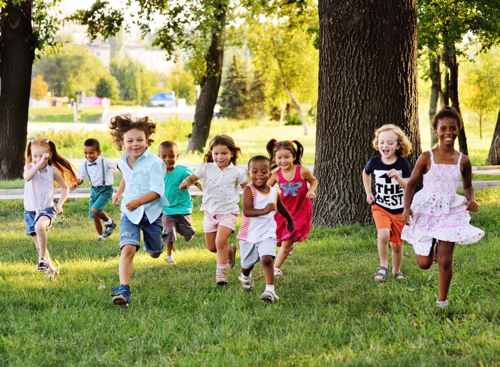 A group of happy children of boys and girls run in the grass on a Sunny summer day .