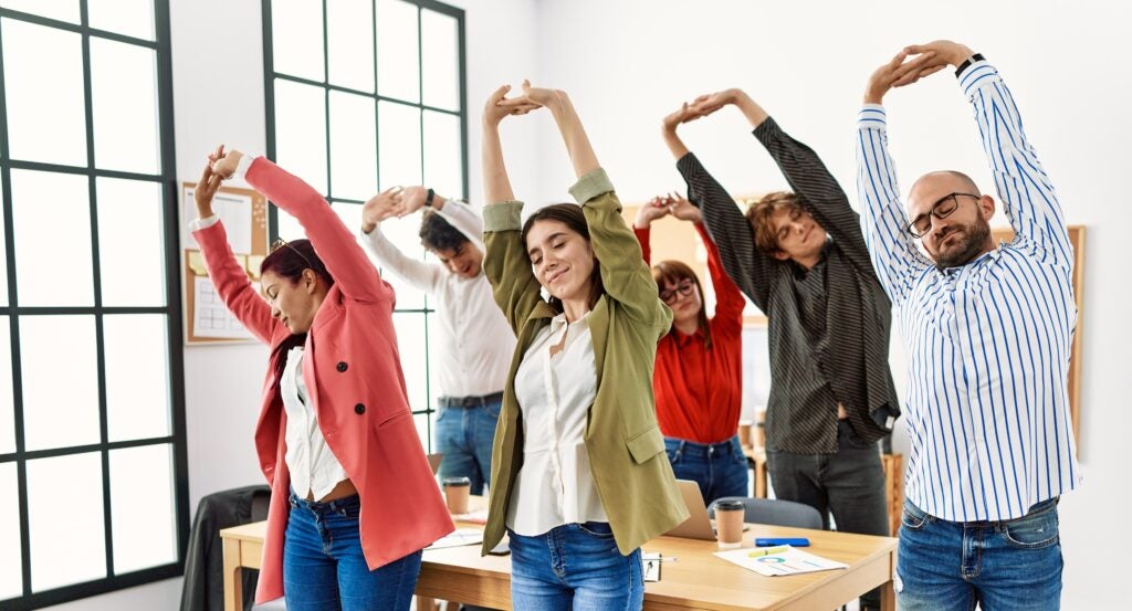 Group of business workers stretching arms in relax time standing at the office.