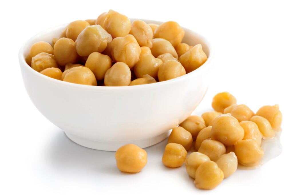 Cooked chickpeas in white bowl with some spilled on side