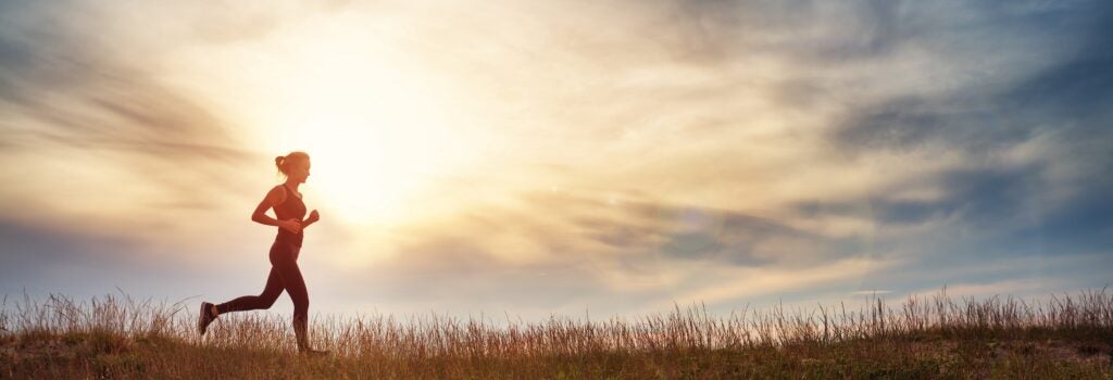 Woman running in a field at sunset.