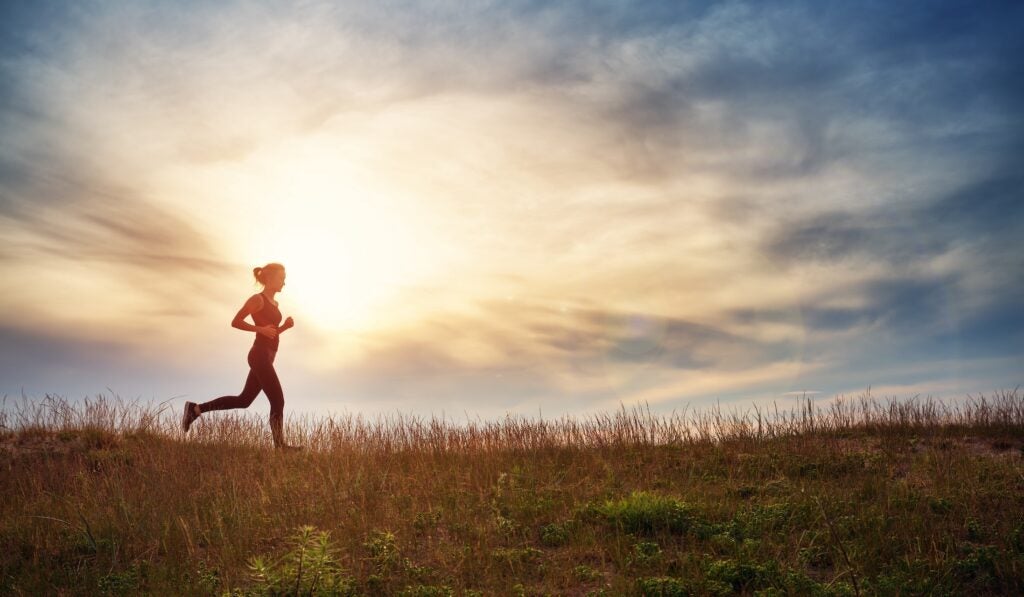 Woman running in a field at sunset.