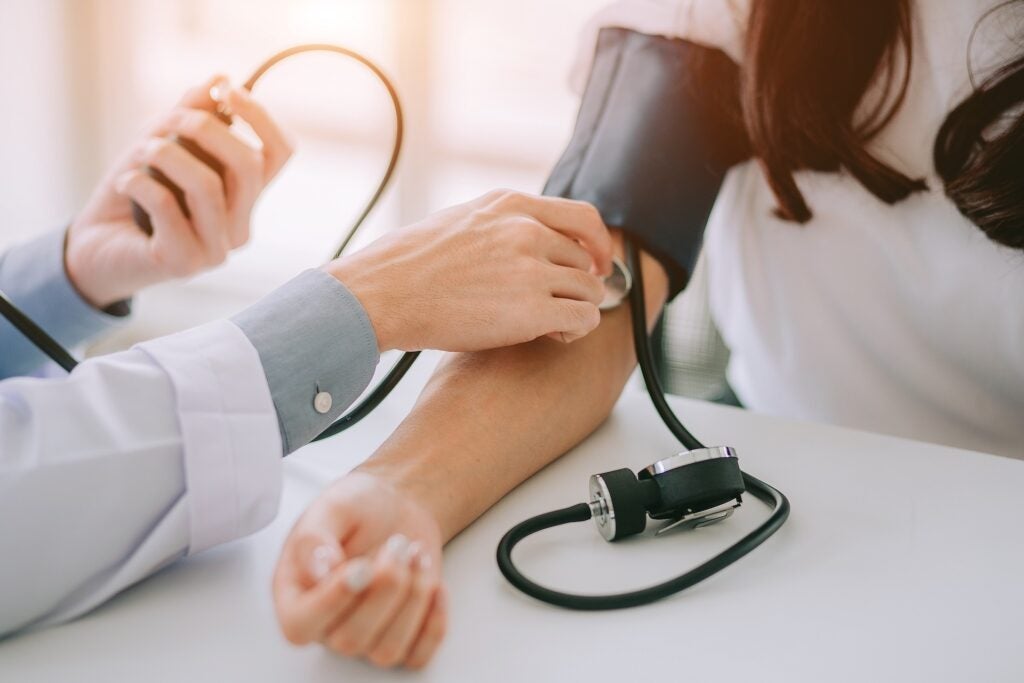 Doctor using sphygmomanometer with stethoscope checking blood pressure of a patient