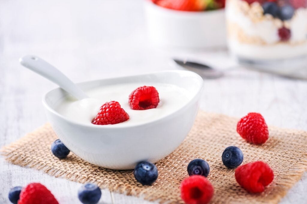 Yogurt with raspberries and blueberries in white bowl