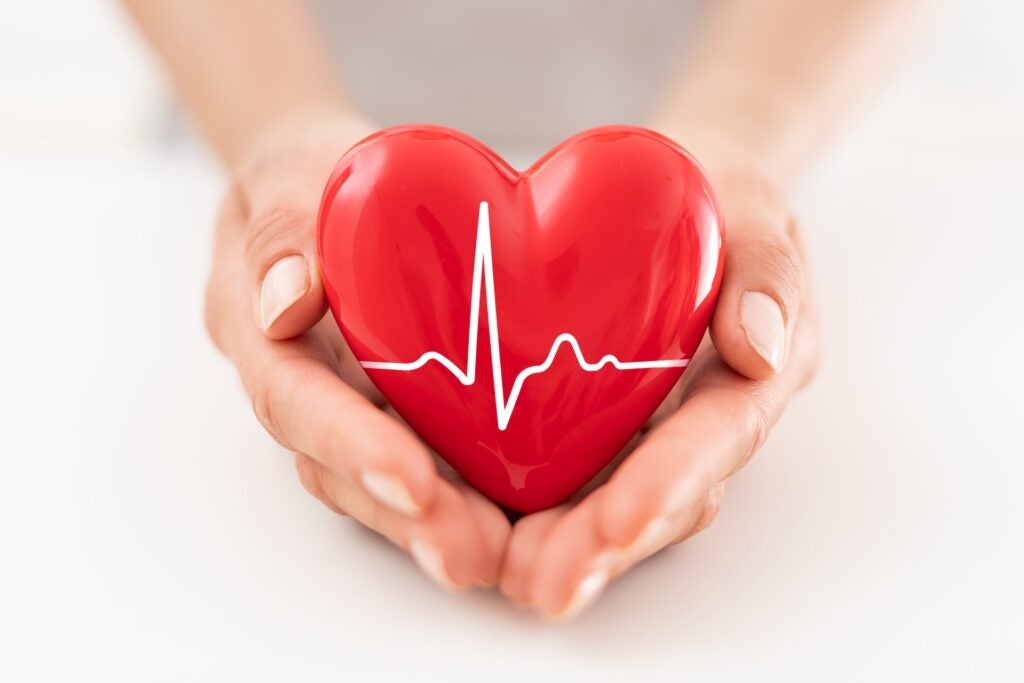 woman is holding a red heart with EKG reading on it