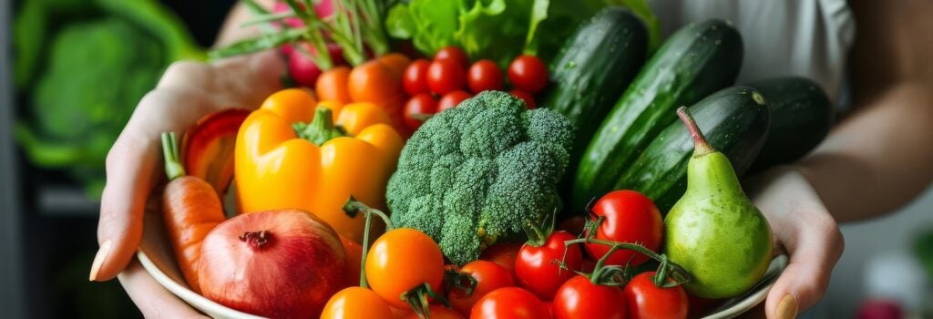 Woman holding bowl of colorful fruits and vegetables