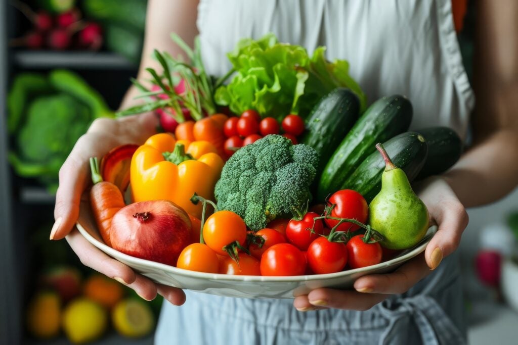 Woman holding bowl of colorful fruits and vegetables