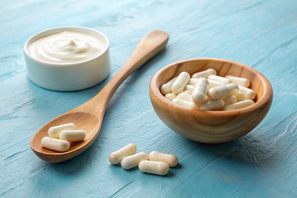 a bowl of yogurt next to a bowl and spoon of probiotic capsules